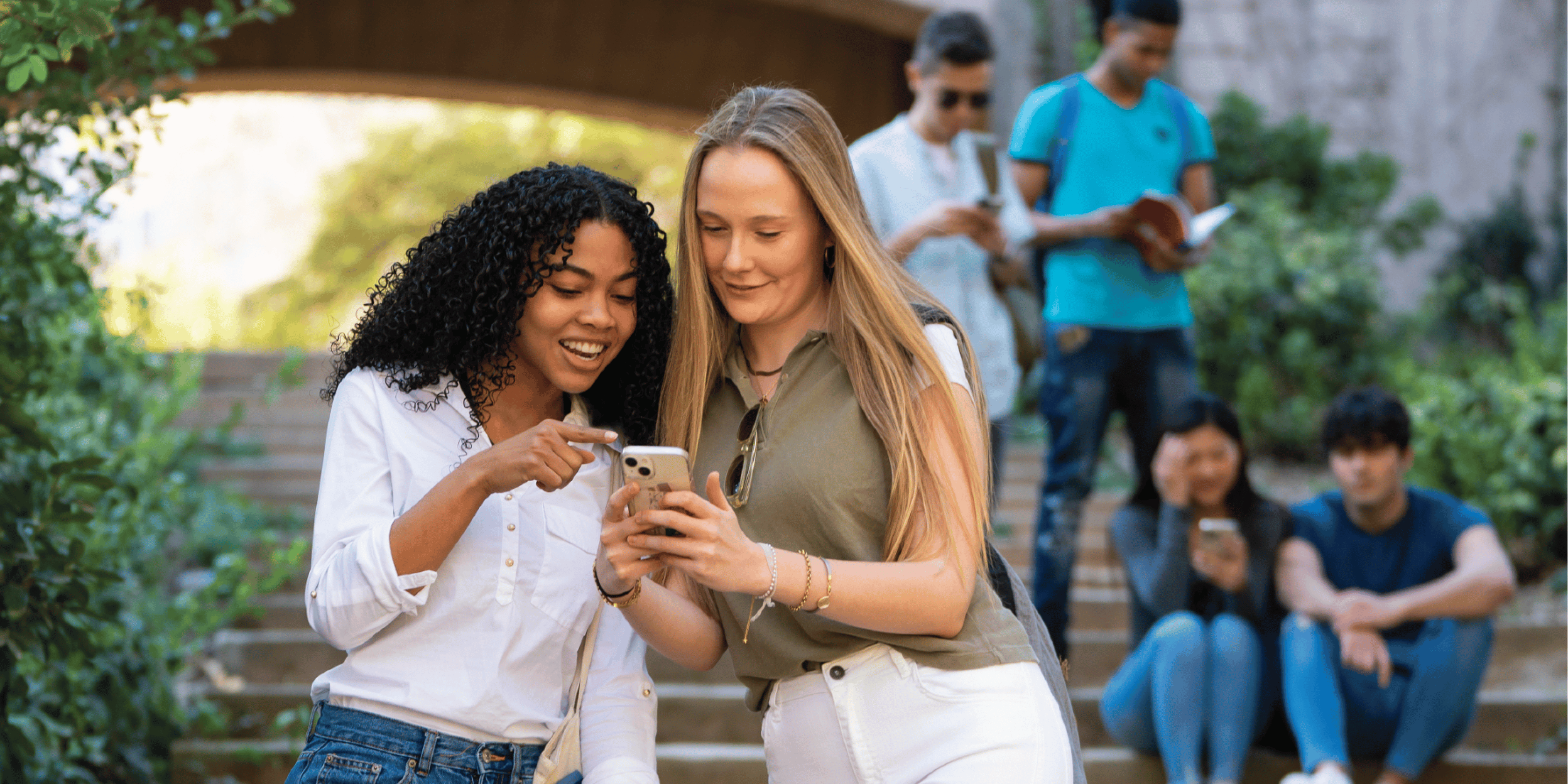 studenci na schodach w parku z telefonami i książkami, getfindia