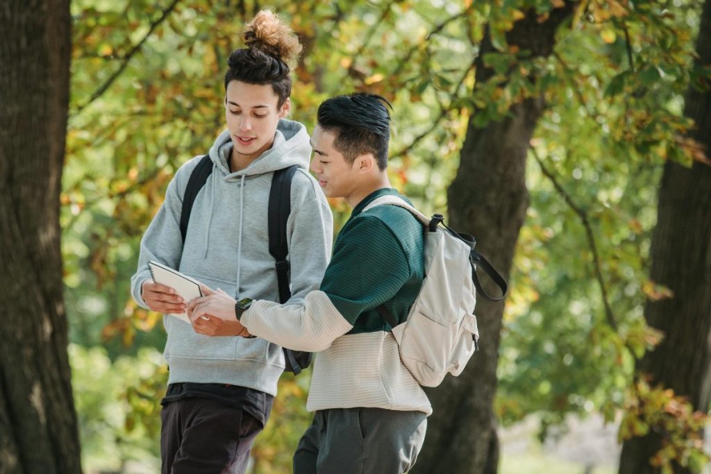 studenci spacerujący w parku, mężczyźni z notesem, getfindia, podróże z plecakiem, planowanie podróży