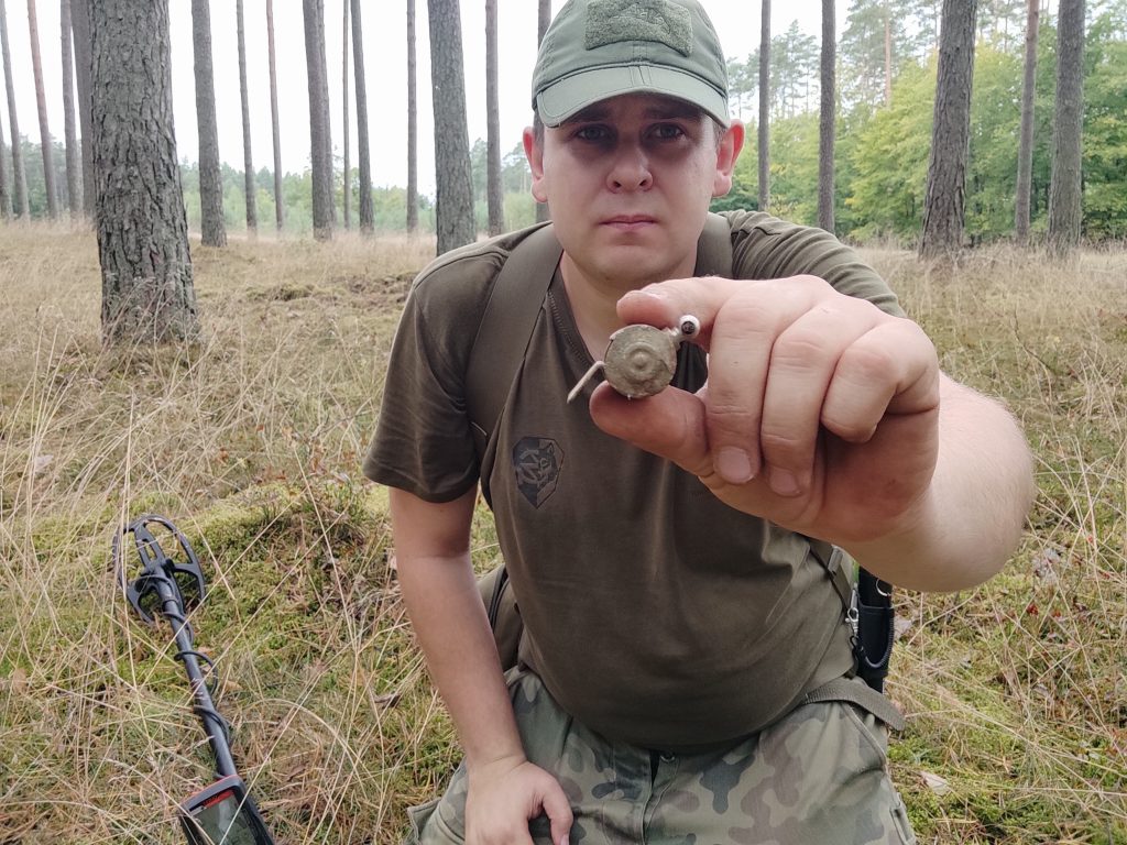 poszukiwacz metali ze swoim znaleziskiem, kawałkiem metalu